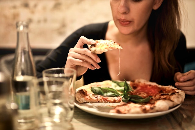 A Woman Eating a Slice of Pizza at a Restaurant